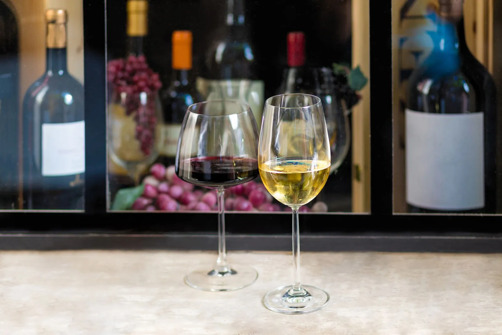 Glasses of red and white wine with bottles and grapes, for a romantic getaway near Saint-Émilion