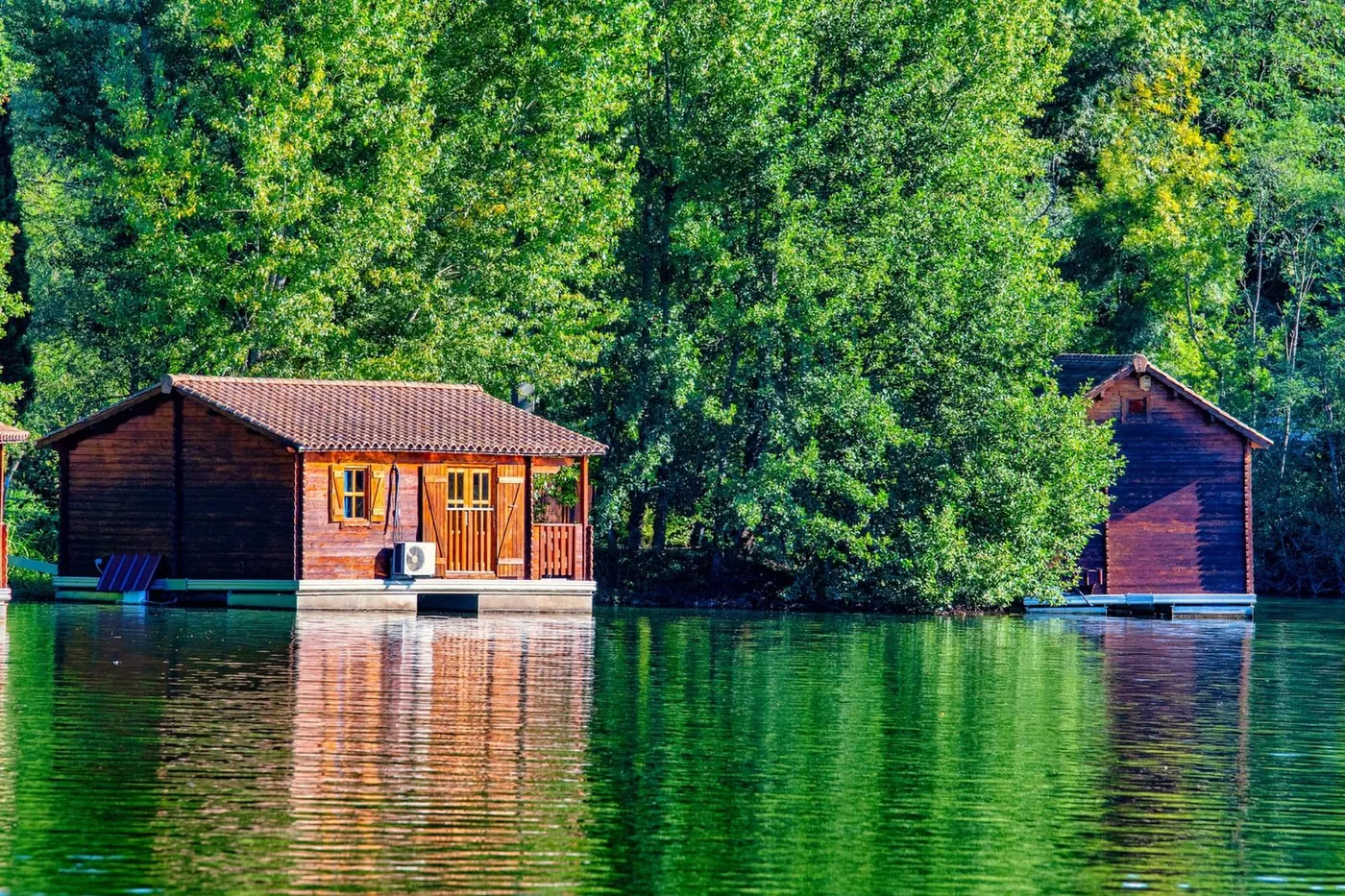 Deux chalets flottants sur le lac, devant la forêt – privatisation du Domaine du Dahu