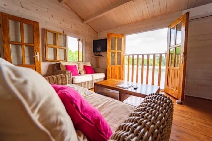 Salon d’un chalet flottant ouvert sur sa terrasse au-dessus du lac – privatisation du Domaine du Dahu